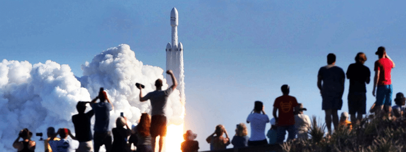 An audience of people watching a rocket launch. 