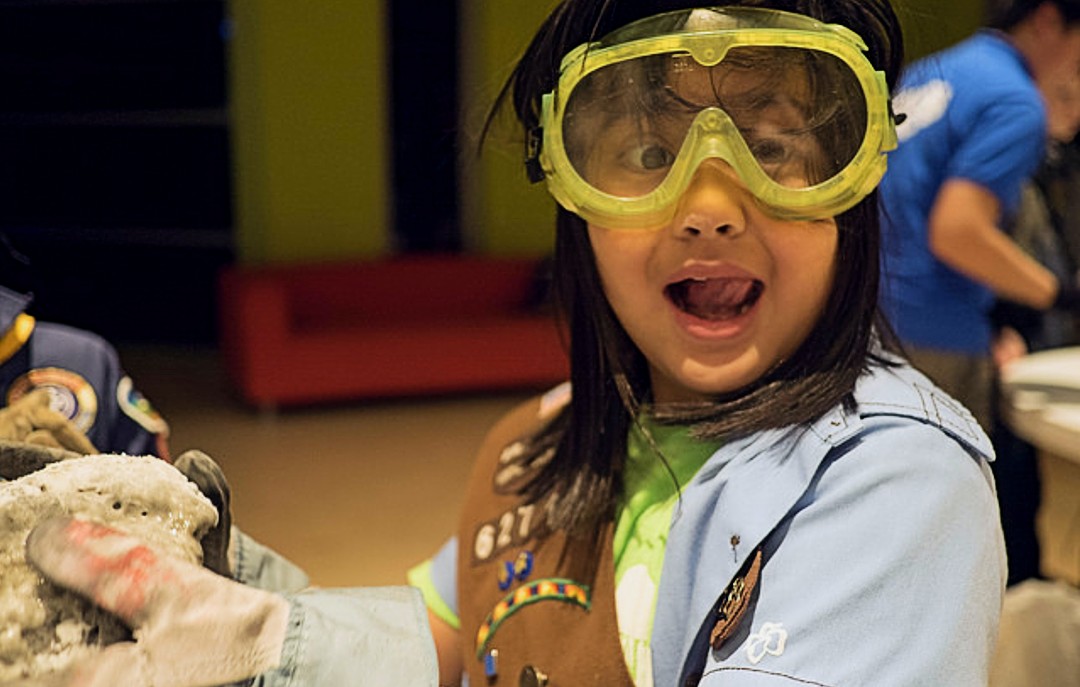 A girl scout wearing yellow googles and making a fun expression for the camera. 