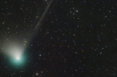 A bright and green comet in the nighttime sky.