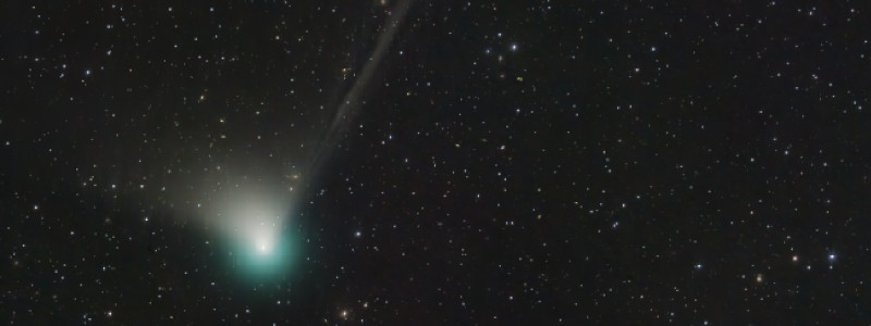 A bright and green comet in the nighttime sky.
